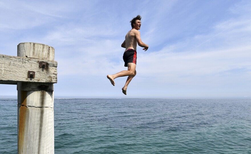 A swimmer jumps from a jetty in an effort to cool off in Adelaide, Australia, as the country experiences record temperatures.