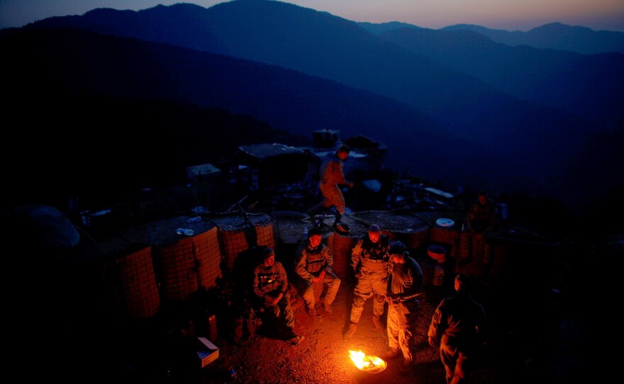 Soldiers with Alpha Company 2-327 (Task Force No Slack), 1st Brigade Combat Team of the 101st Airborne Division make a small fire to keep warm while at nearly 8,000 feet during a security operation for a downed aircraft rescue team working nearby.