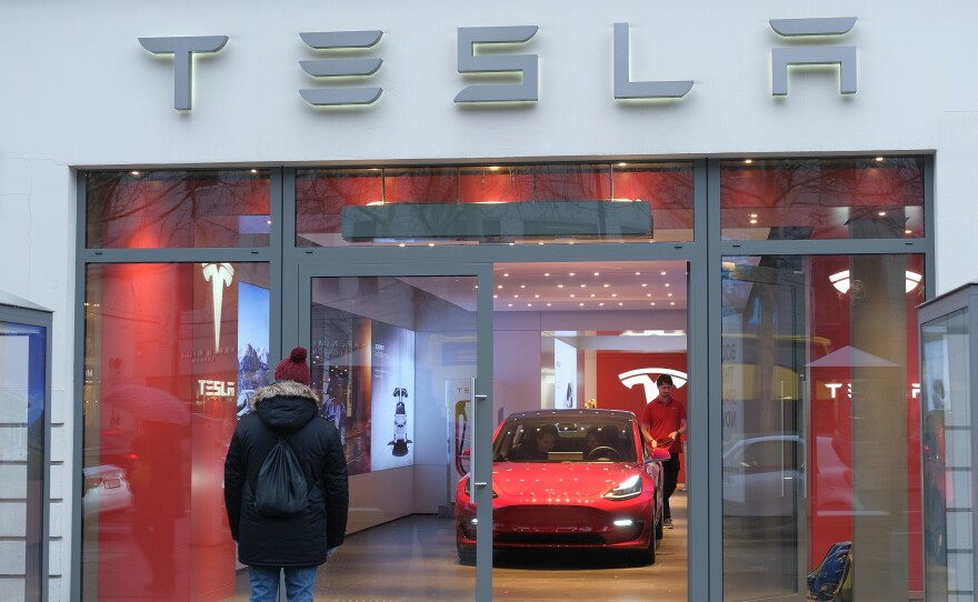 A man stands outside a Tesla dealership in Berlin on Jan. 4. On Friday, Tesla announced it would lay off 7 percent of its workforce, cutting some 3,000 jobs.