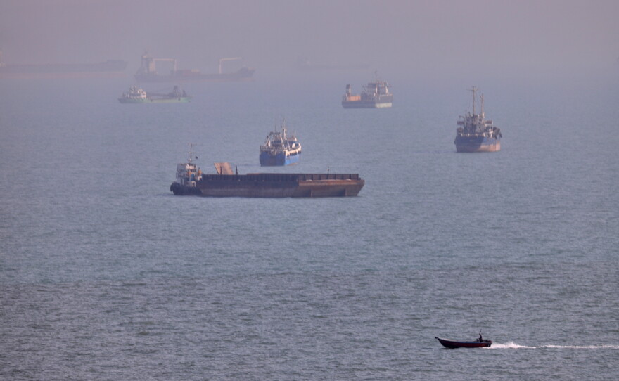 FILE - A small boat sails past cargo ships and other commercial vessels anchored in the Strait of Hormuz off Bandar Abbas, Iran, Wednesday, Aug. 5, 2026. (Amirhosein Khorgooi/ISNA via AP, File)