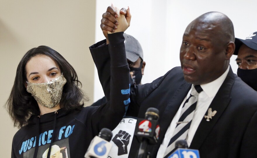 Karissa Hill, daughter of Andre Hill, raises hands with Benjamin Crump, the civil rights attorney representing Hill's family, at a news conference in February after former Columbus police officer Adam Coy was charged with murder in Hill's death.
