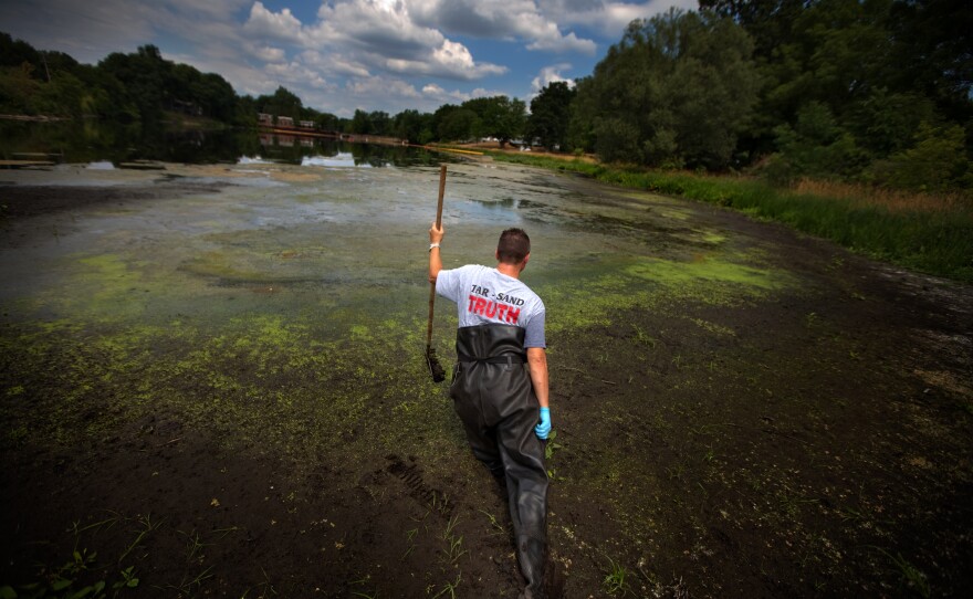 John Bolenbaugh wades through thick mud in in the Kalamazoo River looking for leftover traces of oil from the July 2010 Enbridge oil sands pipeline spill.