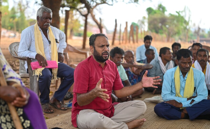 Alok Shukla (center) speaks with community members at the Morga village in India's state of Chhattisgarh. He partnered with local residents to stage protests to protect forests from coal mining interests — including a 10-day march.