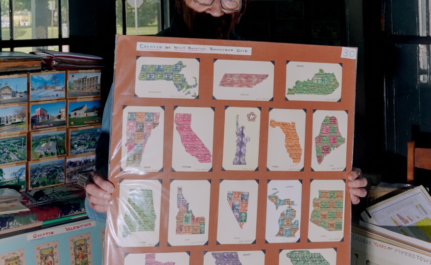 Brown holds up a board of old state postcards in his home in June.