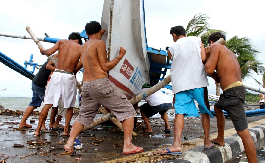 Fishermen carry their outrigger to higher ground Friday in Legazpi City, south of Manila.