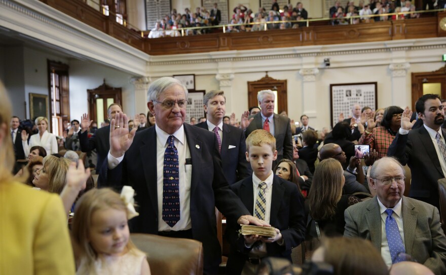 Casey Smith (center) holds a family Bible as his grandfather, Texas state Rep. Jimmie Don Aycock, R-Killeen, takes the oath of office with his fellow legislators on Jan. 13, 2015, in Austin.