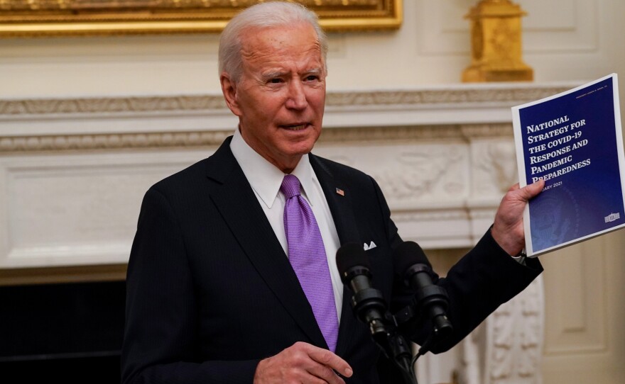 President Joe Biden holds a booklet as he speaks about the coronavirus in the State Dinning Room of the White House, Thursday.