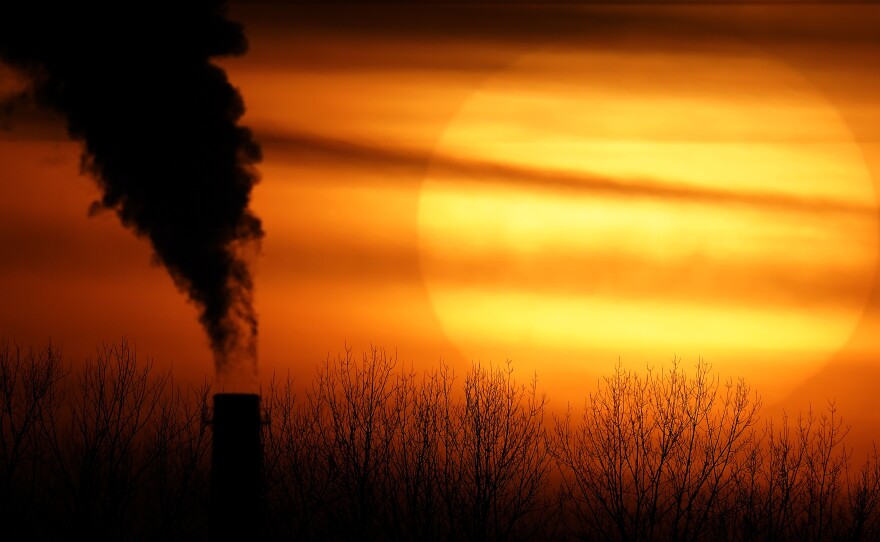 Emissions from a coal-fired power plant are silhouetted against the setting sun in Independence, Mo., in February. President Biden is announcing a new pledge for the U.S. to reduce carbon emissions under the Paris climate agreement.