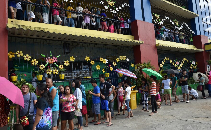 People line up to cast their ballots in the presidential election in suburban Manila.