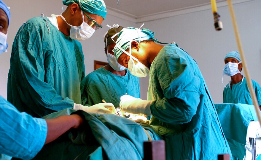 Dr. Dilan Ellegala, left, supervises Dr. Emmanuel Nuwas of Tanzania as he inserts a shunt in a baby with hydrocephalus. Ellegala has played a key role in training local doctors, as described in the new book <em>A Surgeon in the Village. </em>Early on, he trained a hospital staffer who wasn't a doctor to do brain surgery.