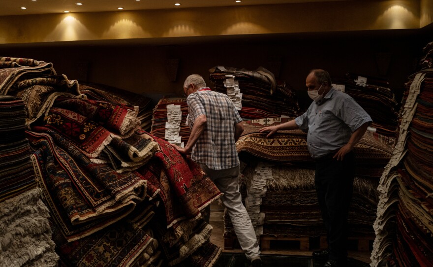 Ferudun Ozgumus (left) walks through a carpet shop above a basement containing Byzantine-era ruins.