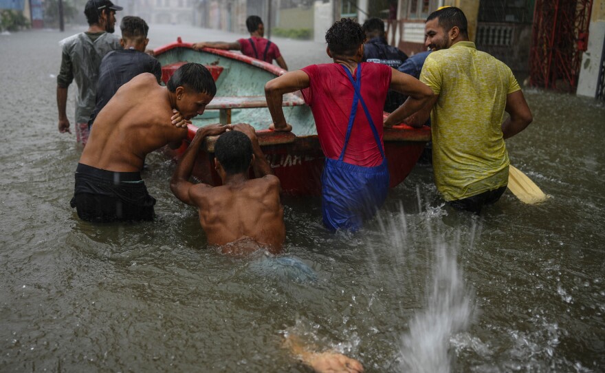 Volunteers push a boat through a street flooded by heavy rains to rescue a neighbor in Havana on Friday.