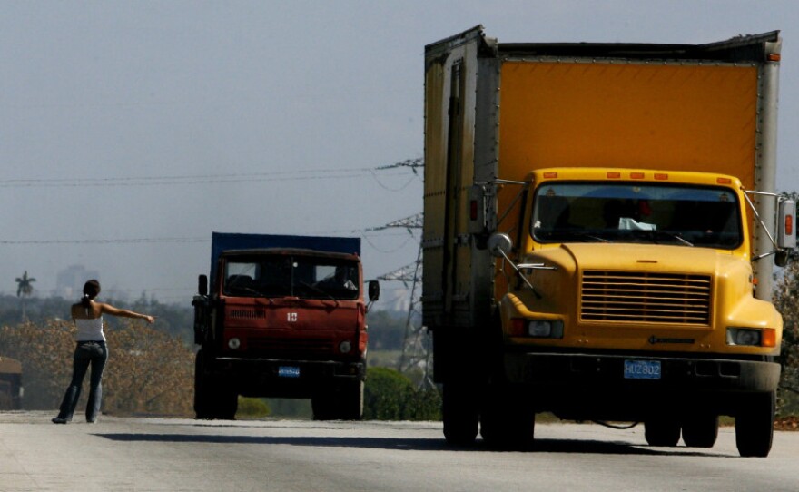 A woman hitchhikes on a highway outside Havana.