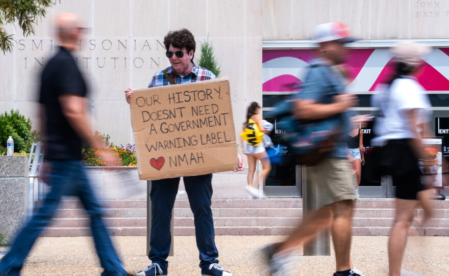 Mark Ehlers holds a sign outside the National Museum of American History in July 2026.