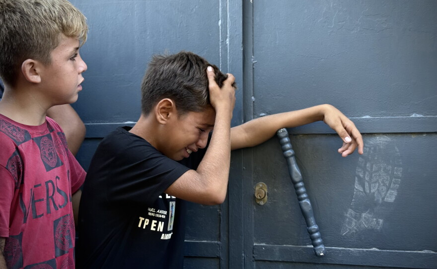 A Palestinian child whose brother was killed in an Israeli airstrike cries at the door of a morgue at Al-Shifa Hospital in Gaza City on Aug. 19, 2026.