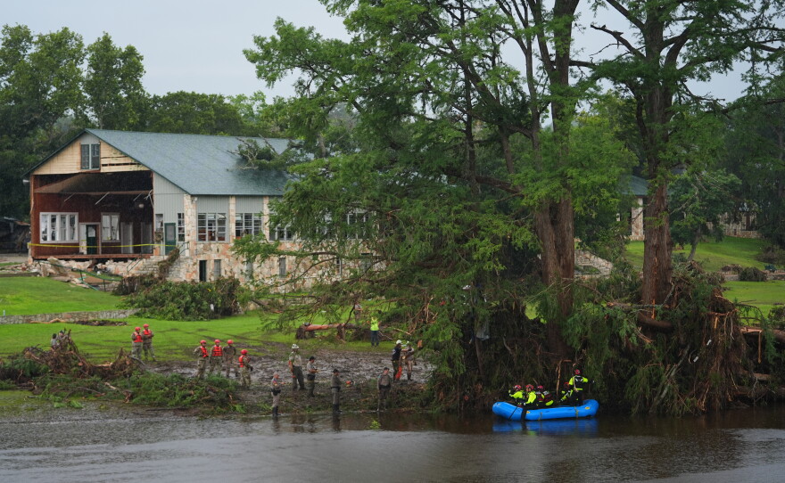 Rescue workers are seen on land and on a boat as they search for missing people near Camp Mystic in Hunt, Texas, along the Guadalupe River after a deadly flash flood swept through the area in July 2025.