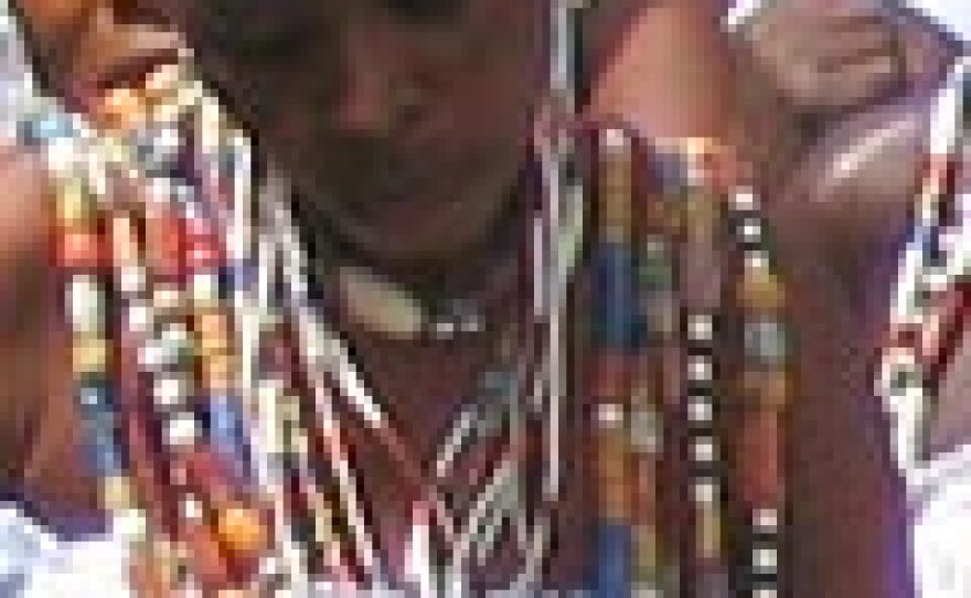 Woman arrives dancing and singing at an Epe Ekpe festival, dressed in a traditional white toga.