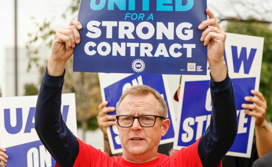 UAW members hold signs outside after walking out from the GM parts distribution center in Bolingbrook, Ill., on Sept. 22, 2023. President Biden said he would join workers on the picket line in Michigan next week.