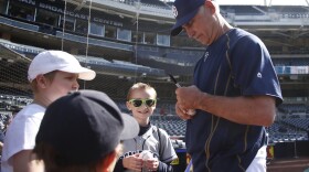 San Diego Padres manager Bud Black signs autographs during warmups prior to a baseball game against the New York Mets, June 3, 2015, in San Diego. 