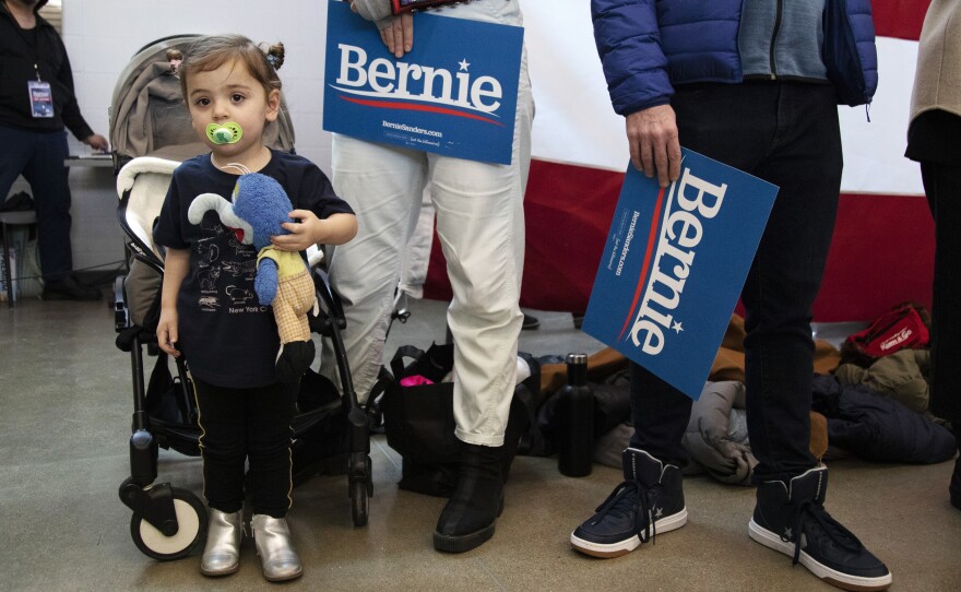 Goldie Federico-Rubin, 2, of Des Moines, stands next to her mom, Laura Federico, as they list to Democratic presidential candidate Sen. Bernie Sanders (I-Vt.) Saturday, Jan 11, 2020 during a campaign event at Berg Middle School in Newton, Iowa.