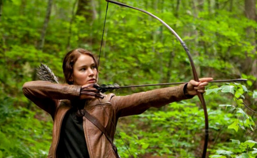 Jennifer Lawrence aims an arrow in <em>The Hunger Games</em>. The central character of the film based on Suzanne Collins' books relies on her ability with a bow to survive.