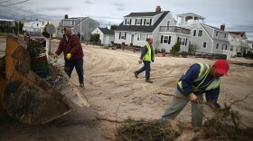 Workers clean up debris left by Superstorm Sandy in Long Beach Island, N.J., on Wednesday. The storm may lead to layoffs as business losses mount, but also could result in hiring related to rebuilding.