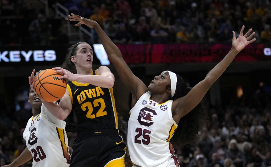 Iowa guard Caitlin Clark (22) passes over South Carolina guard Raven Johnson (25) during the first half of the Final Four college basketball championship game in the women's NCAA Tournament, Sunday, April 7, 2024, in Cleveland.