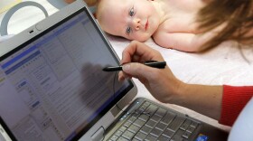 Patient William Wishart, age 4 months, looks on as Dr. Melanie Walker uses a portable computer to enter information from his exam into an electronic medical records system, in North Raleigh, N.C., in November.