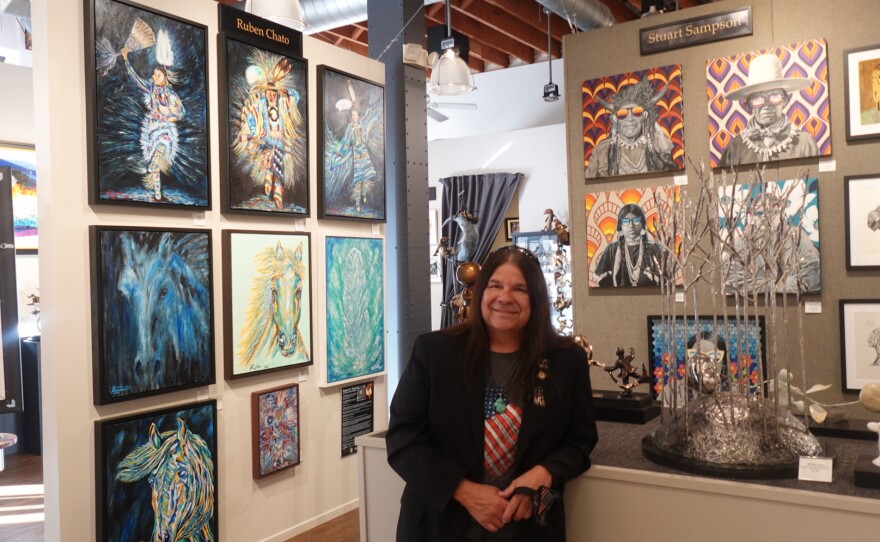 Ruben Chato Hinojosa standing next to his art in Exclusive Gallery Collections for Native American Heritage Month on Nov. 10th, 2025.