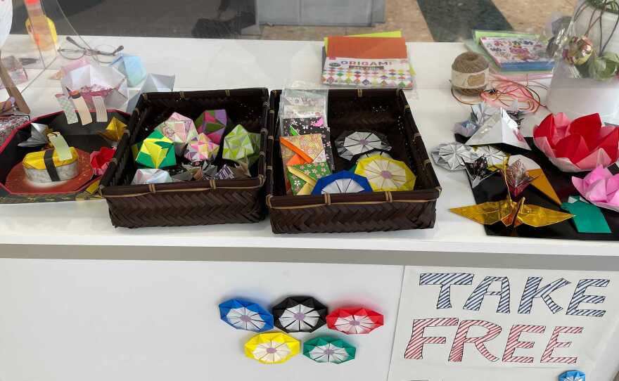 Volunteers make origami to give to visiting journalists at the Tokyo Olympics.