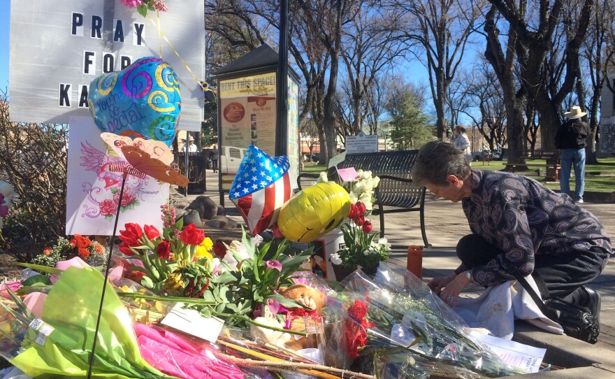 A woman kneels near a makeshift memorial for Kayla Mueller in Prescott, Ariz.