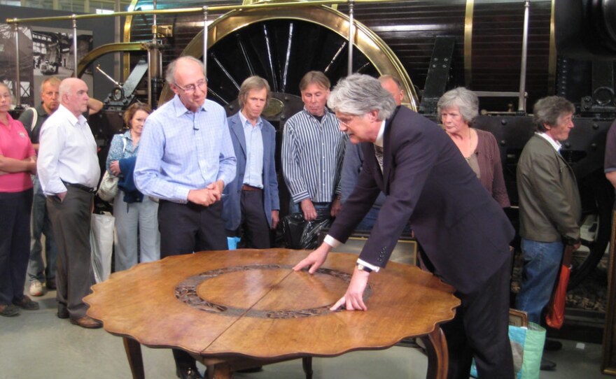 Furniture specialist Christopher Payne examines a table.