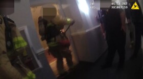 Police and firefighters, pictured in this screenshot from police body-worn camera footage released on May 13, 2019, open the door to Joseph Darwish's apartment shortly before he opened fire on them, wounding two officers, on June 23, 2018. 

