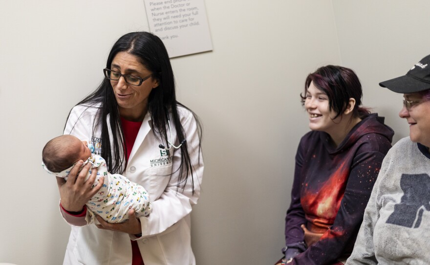 Dr. Mona Hanna-Attisha holds newborn baby Rowan, who was in for a wellness checkup with his 19-year-old mom, Hailey Toporek, and her mother, Heather Toporek, at the Hurley Children's Clinic in Flint.