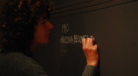 Artist Clare Patey outlines the history of copper in Arizona on the gallery wall. (Photo by Murphy Bannerman)