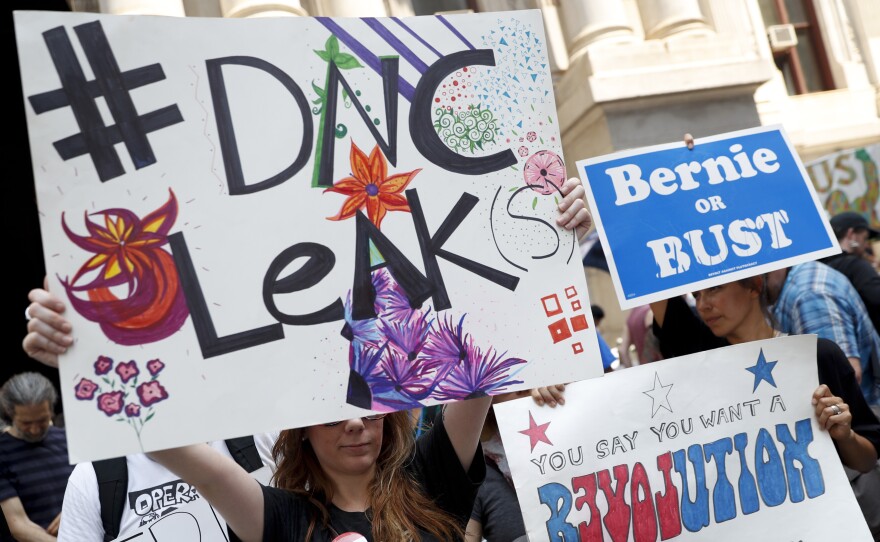 Demonstrators held signs outside the Democratic National Convention on Monday in Philadelphia. On Sunday, Debbie Wasserman Schultz, announced she would step down as DNC chairwoman at the end of the party's convention, after thousands of internal DNC emails were posted by the website Wikileaks.