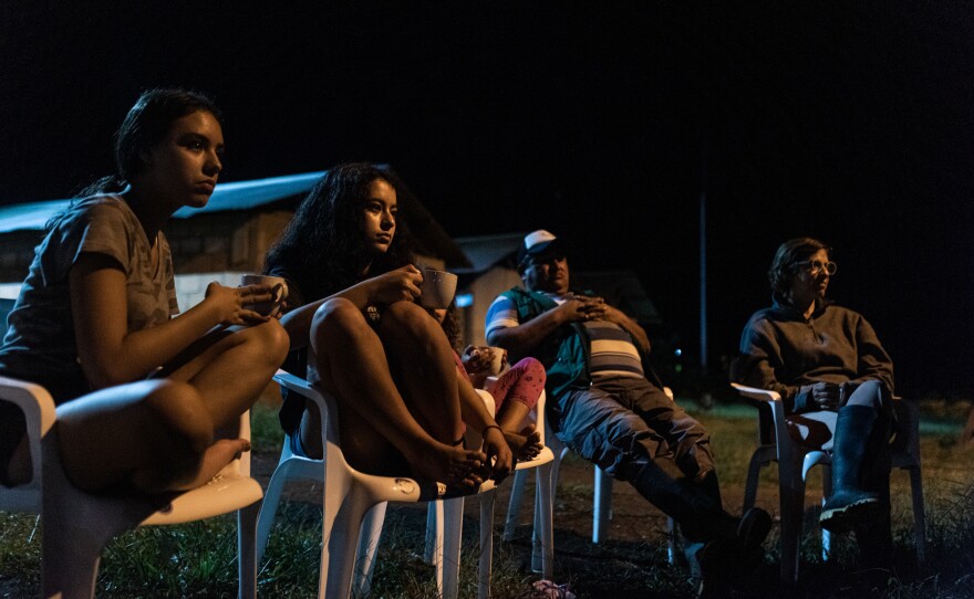 Tourists sit around a campfire at the resettlement camp for former FARC rebels, who told war stories and apologized for the human rights abuses the guerrillas committed during the conflict.