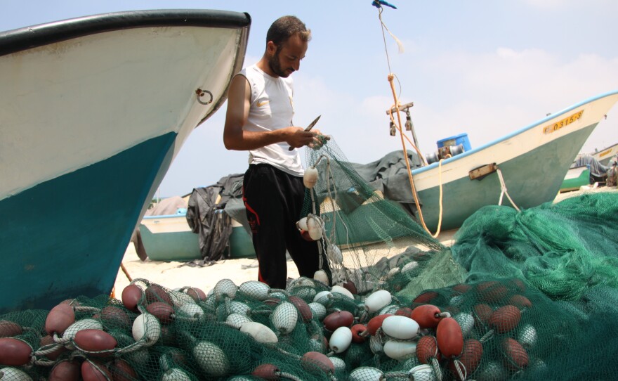 Khalil Najjar, mending his nets, says the Israeli navy enforces a 500-meter boundary from shore and has fired warning shots near fishing boats.