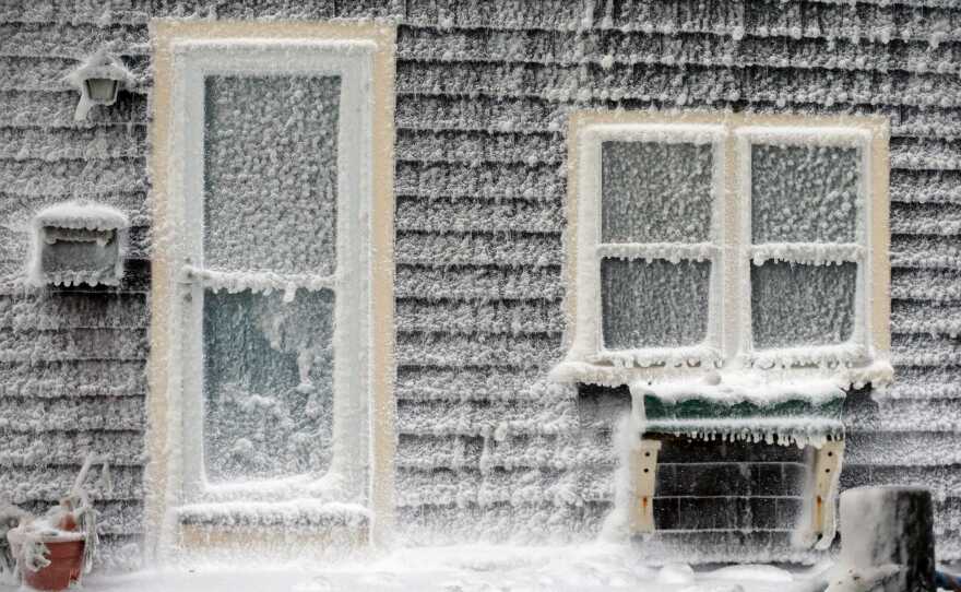 Ice from breaking waves coats a house along the shore in Scituate, Mass.