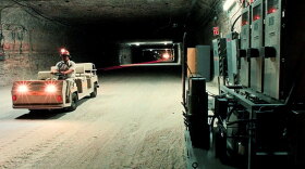 A worker drives an electric cart past air monitoring equipment in a storage room of the Waste Isolation Pilot Plant in Carlsbad, N.M.