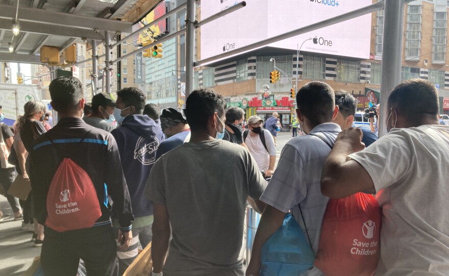 Asylum-seekers who have recently arrived in New York on a bus from Texas wait for ride-share vehicles, organized by a mutual aid group, to take them into the city.