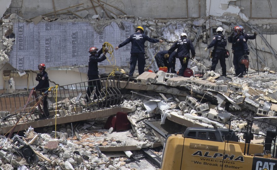 Members of the South Florida Urban Search and Rescue team look for possible survivors in the partially collapsed 12-story Champlain Towers South condo building on Saturday. Rescuers found an additional body Saturday.