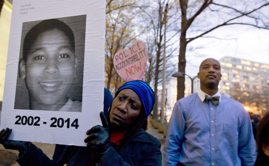 In a photo taken Dec. 1 of last year, Tomiko Shine holds up a picture of Tamir Rice during a protest. It has been nearly a year since then, but a grand jury has not reached a decision on the case.