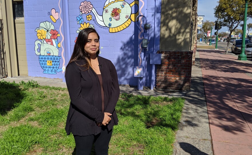 Mimi Gonzalez Martinez, 17, stands in front a pastel mural featuring flowers and tea cups that she painted on the side of the Treasure Trove antique shop in San Diego's City Heights neighborhood, March 28, 2019.