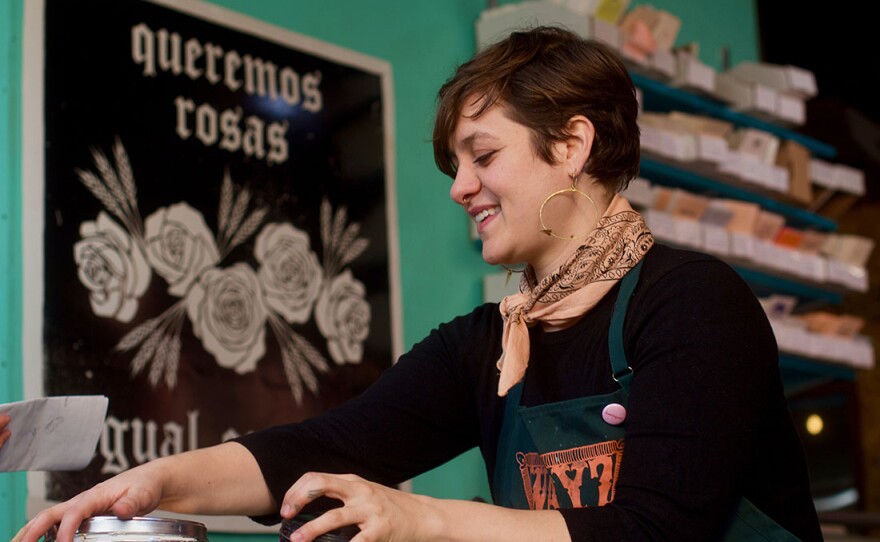 Film still from “La Tienda." Daniela preps ink.