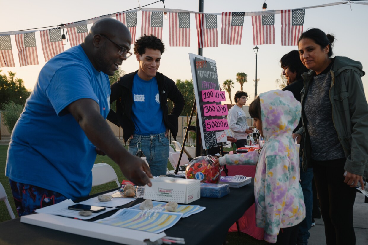 William Cooper, left, director of the Becoming Project, chats with Abby Guardado as she takes a piece of candy from their jar during an information event organized by the ACLU’s Imperial Valley team, along with five other local advocacy organizations, on Oct. 18, 2024. The coalition is hoping to register hundreds of new voters and get people energized about casting their ballots ahead of the November election.