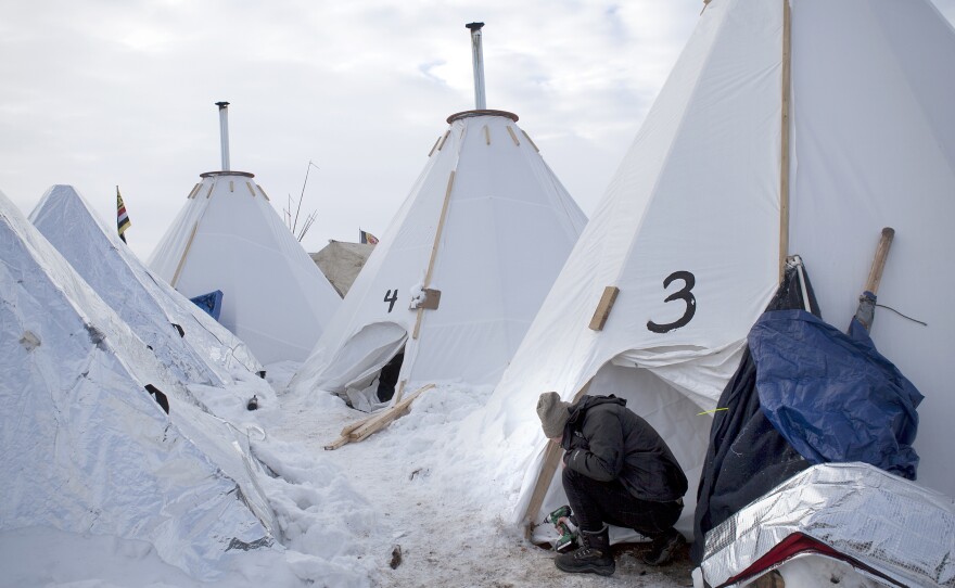 Jacob Brooks makes adjustments to one of the camp's many "tarpees," a winterized teepee made of tarp with a built-in chimney, designed by Paul Cheokoten Wagner. There are roughly 60 tarpees around various camps now, and Wagner has fundraised enough for another 20 more.