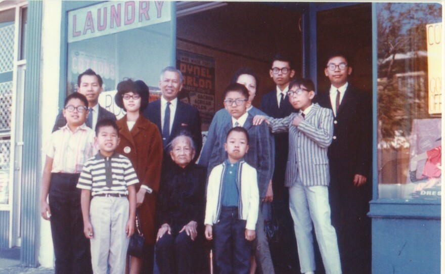 Corky Lee and his family gather for a portrait in front of their laundry in Queens, NY. (Lee is third from the right in suit and tie in back row.)