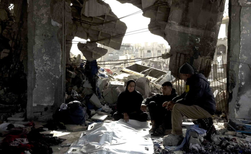 Members of the Abu Naser family sit beside the body of one of the victims recovered nearly a year and a half after their family's apartment building was struck in northern Gaza.
