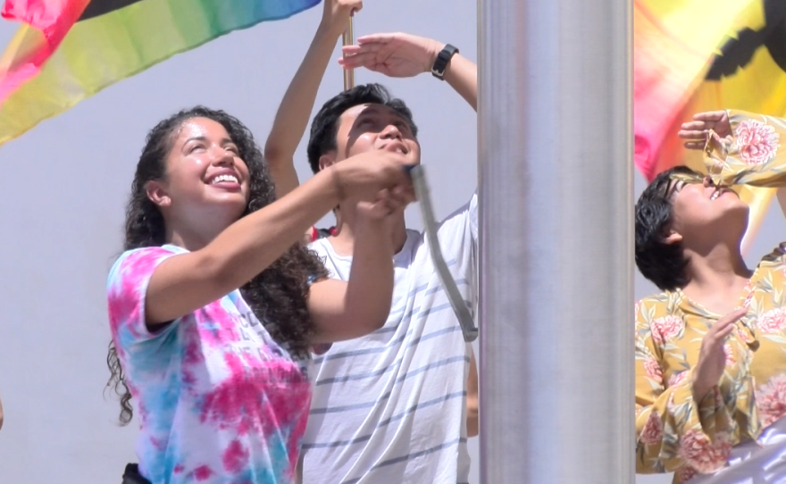 San Diego State University student Amber McKinney helps raise a rainbow flag to celebrate Pride, July 7, 2017.